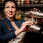 bartender-girl-holding-two-steel-cocktail-shakers-121938870